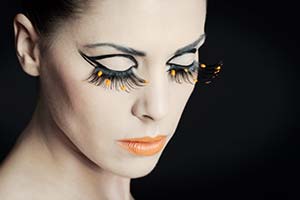 Frauenporträt mit orangenen Farbtropfen auf Wimpern